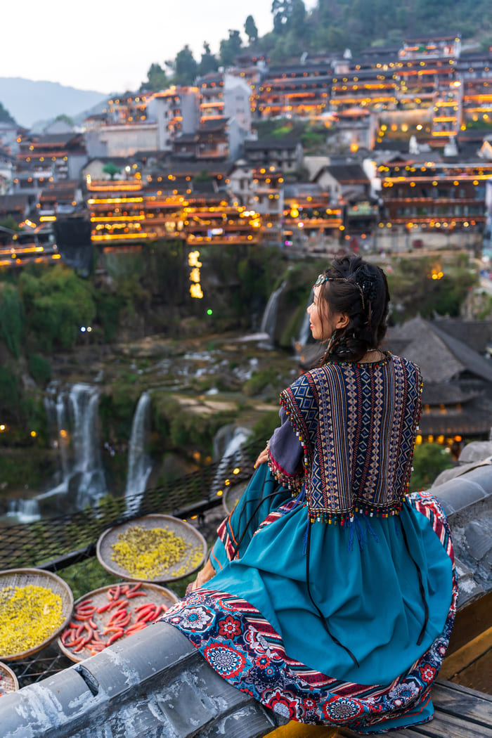 Mujer china de frente a lago mirando al horizonte